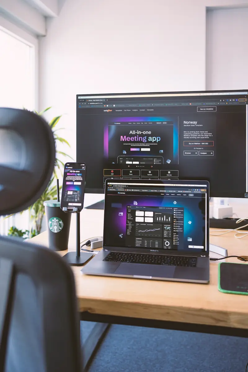 Responsive web design shown on a monitor, laptop and phone on one desk